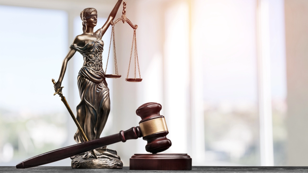 Eine Statue von Justizia liegt neben einem Richterhammer auf einem Tisch