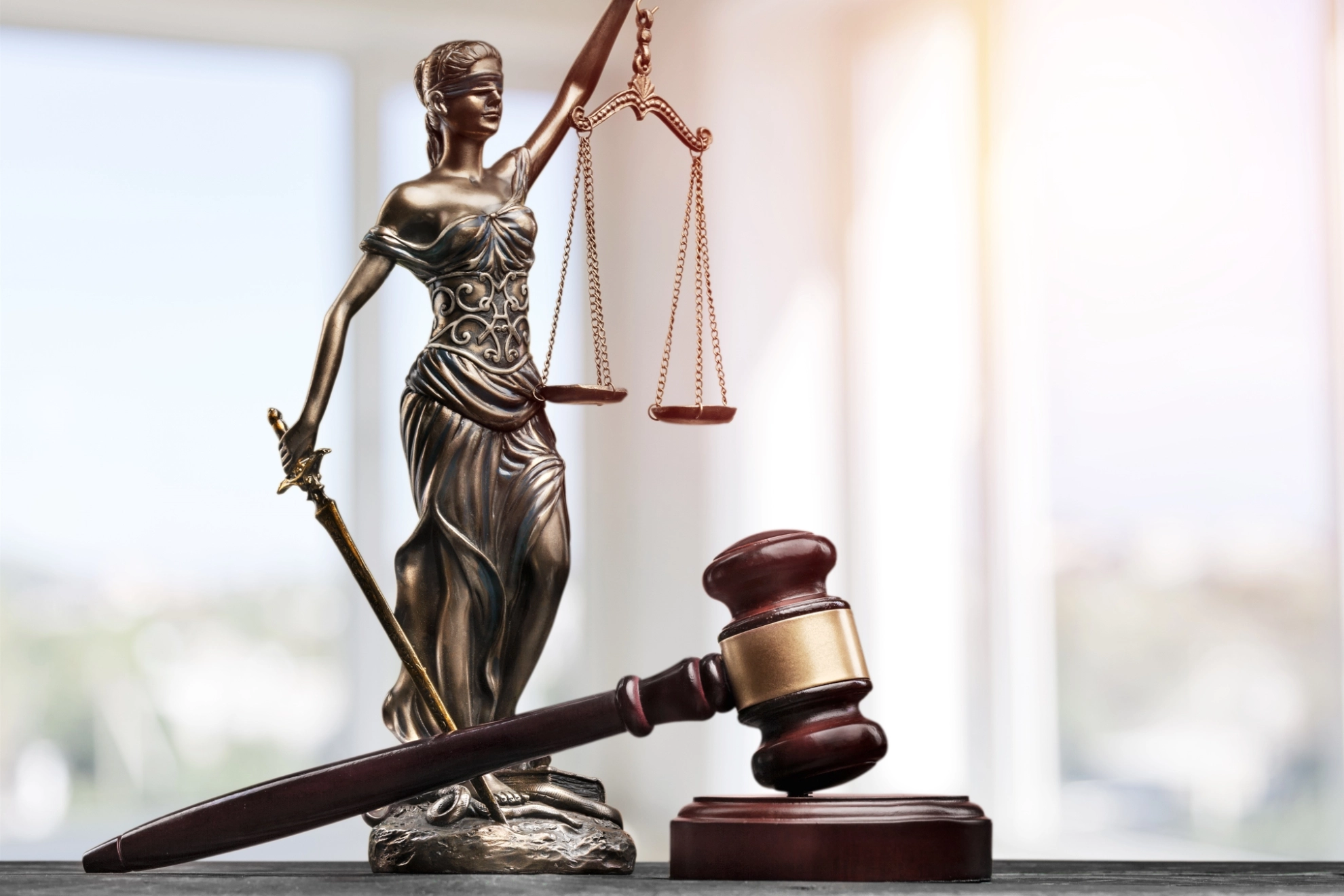 Eine Statue von Justizia liegt neben einem Richterhammer auf einem Tisch