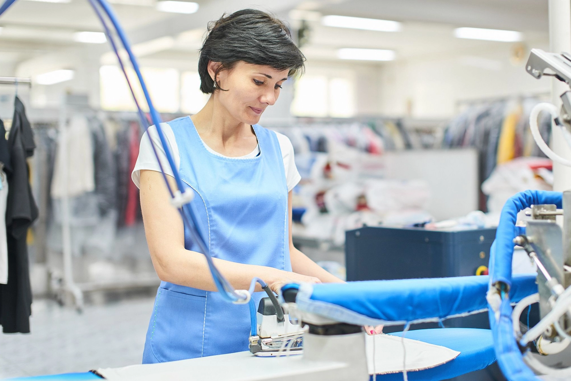 Textile Dienste: Arbeiterin bügelt Kleidung 